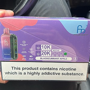 Purple-blue retail box of Fumot disposable vapes labeled 'Blackcurrant Apple,' showing device images, puff counts '10K/20K puffs,' nicotine percentages (0, 2%, 3%, 5%), and a large warning reading 'This product contains nicotine which is a highly addictive substance.'