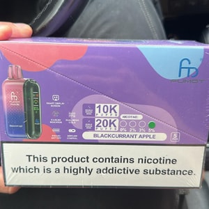 Purple-blue retail box of Fumot disposable vapes labeled 'Blackcurrant Apple,' showing device images, puff counts '10K/20K puffs,' nicotine percentages (0, 2%, 3%, 5%), and a large warning reading 'This product contains nicotine which is a highly addictive substance.'