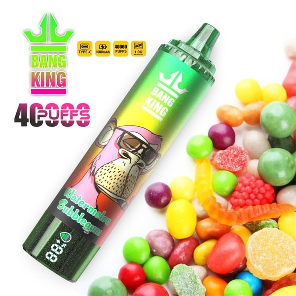 Green gradient disposable vape pen labeled BANG KING with a sunglasses-wearing cartoon monkey and the flavor Watermelon Bubblegum, pictured diagonally among assorted colorful gummy candies and round sweets