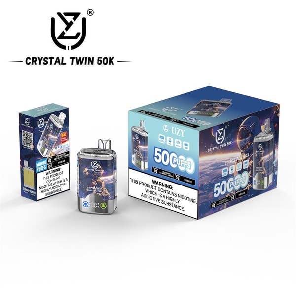 A shiny rectangular 'Crystal Twin 50K' disposable vape device displayed beside two blue retail boxes with the UZY logo, visible '50 puffs' branding, flavor icons and a prominent nicotine-warning label.